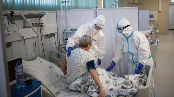 Медицинские работники и пациент в отделении реанимации и интенсивной терапии в госпитале для больных COVID-19 