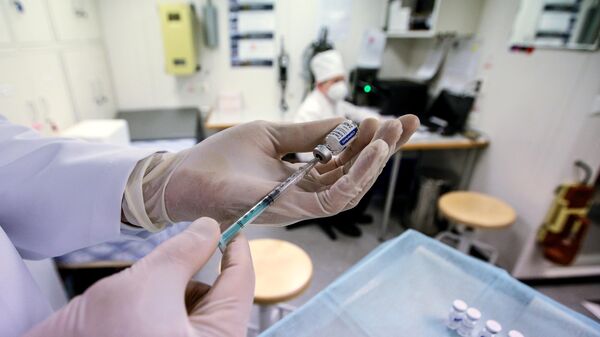 Медицинский работник набирает в шприц вакцину от COVID-19
