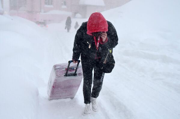 Девушка во время снегопада на одной из улиц в Норильске
