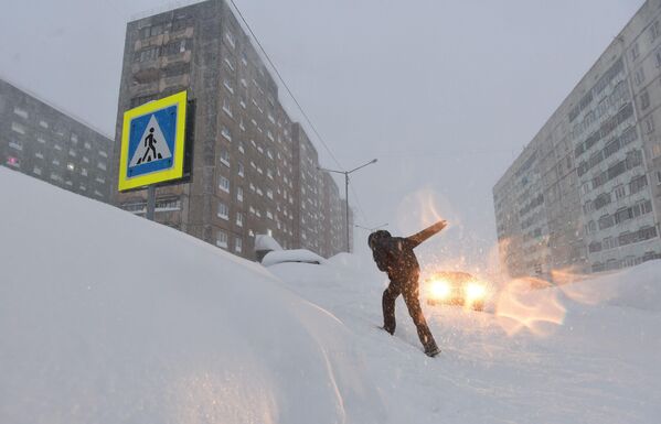 Молодой человек во время снегопада на одной из улиц в Норильске