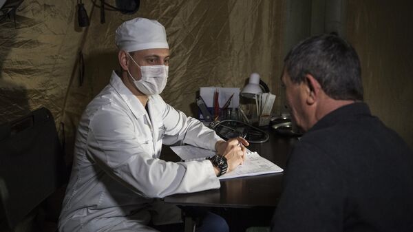 Врач проводит прием пациента на базе госпиталя развернутого Министерством обороны России на территории аэропорта в Степанакерте