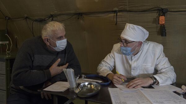 Врач проводит прием пациента на базе госпиталя развернутого Министерством обороны России на территории аэропорта в Степанакерте