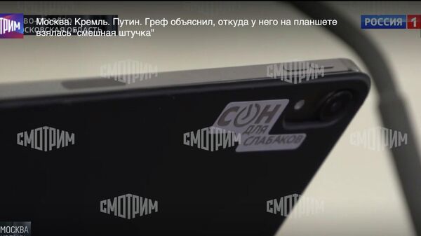 Наклейка на планшете председателя правления Сбербанка России Германа Грефа во время эфира на телеканале Россия 1
