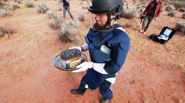 Член команды JAXA с капсулой с грунтом, собранным космическим зондом Хаябуса-2 на астероиде Рюгу в Вумера, Австралия