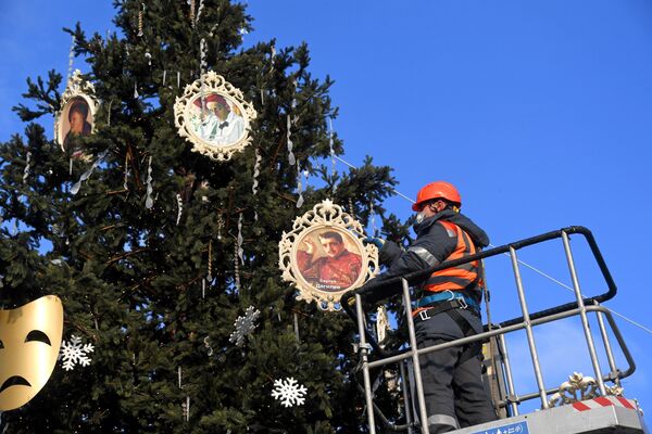 Рабочий вешает портрет Сергея Дягилева на ёлку, установленную возле Северного речного вокзала в Москве