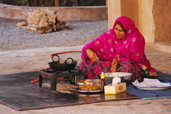 Женщина готовит еду в крепости Низва в Омане