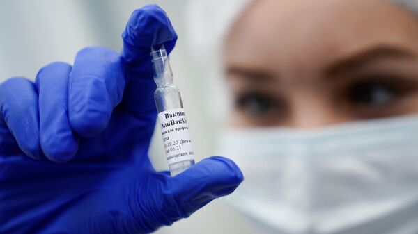 Медработник демонстрирует вакцину ЭпиВакКорона в процедурном кабинете 