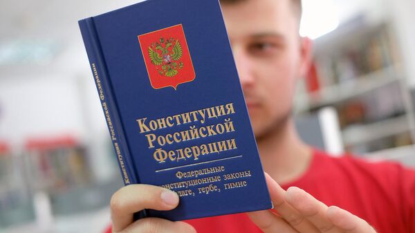 Молодой человек держит Конституцию Российской Федерации