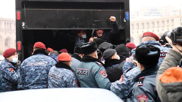 Сотрудники правоохранительных органов сажают в машину одного из задержанных участников акции протеста в Ереване