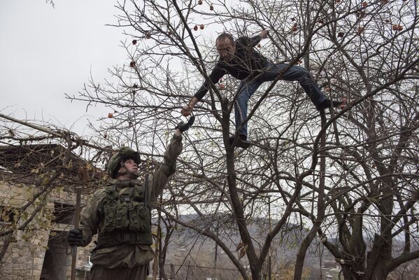 Местный житель угощает специалиста Международного противоминного центра Минобороны России гранатом вблизи Степанакерта в Нагорном Карабахе