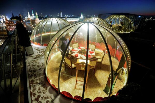 Официант накрывает стол внутри прозрачного купола на крыше отеля Ritz-Carlton в Москве, Россия