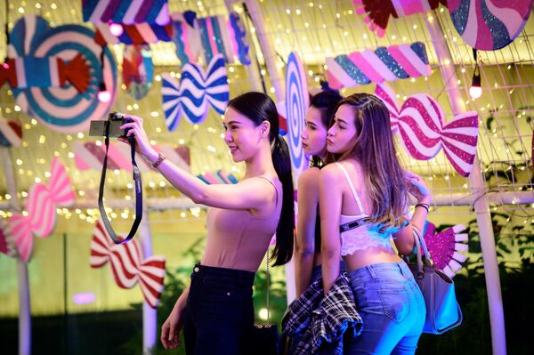 Девушки фотографируются возле торгового центра в Бангкоке