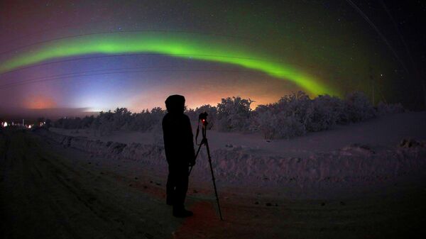 Мужчина фотографирует северное сияние на трассе Серебрянка в Мурманской области