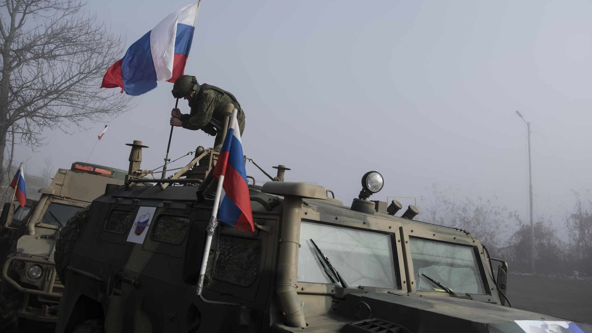 Российский миротворец устанавливает флаг на бронеавтомобиле - РИА Новости, 1920, 17.02.2022