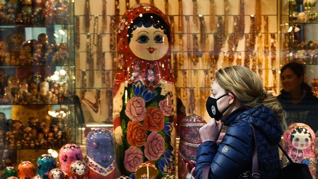 Девушка в маске проходит мимо сувенирного магазина