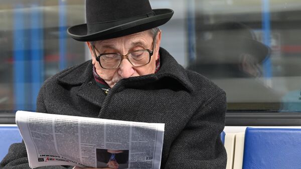 Мужчина читает газету во время поездки в метро