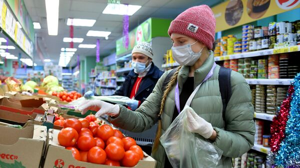Девушка выбирает помидоры в супермаркете