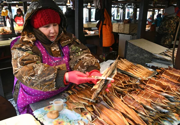 Женщина продает омуль на рыбном рынке в Листвянке