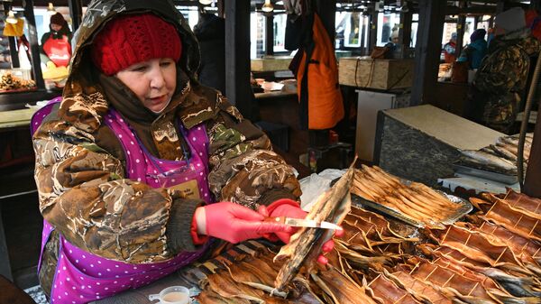 Женщина продает омуль на рыбном рынке в Листвянке