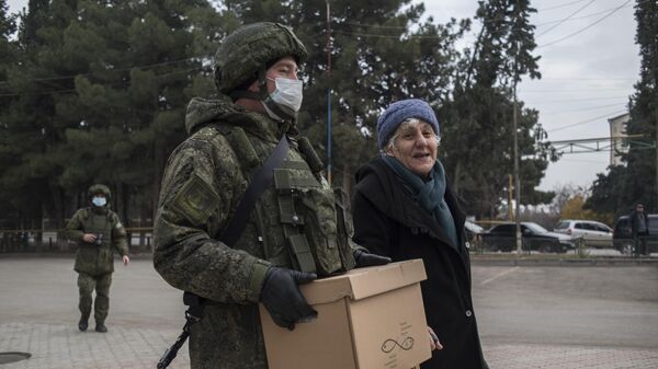 Военнослужащий российского центра по примирению враждующих сторон раздает гуманитарную помощь жителям города Мартакерт в Нагорном Карабахе