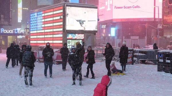 Прохожие во время снегопада на Тайм-сквер в Нью-Йорке