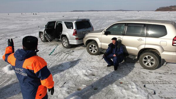 Сотрудник МЧС ведет разъяснительную беседу с рыбаком-любителем об опасности выезда на лед на автомобиле