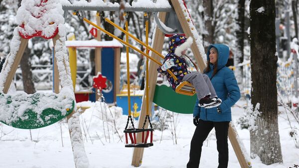 Женщина с ребенком на детской площадке Фестивального сквера в Краснодаре после снегопада