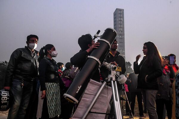 Люди наблюдают в телескоп за встречей Юпитера и Сатурна в районе Майдана в Калькутте