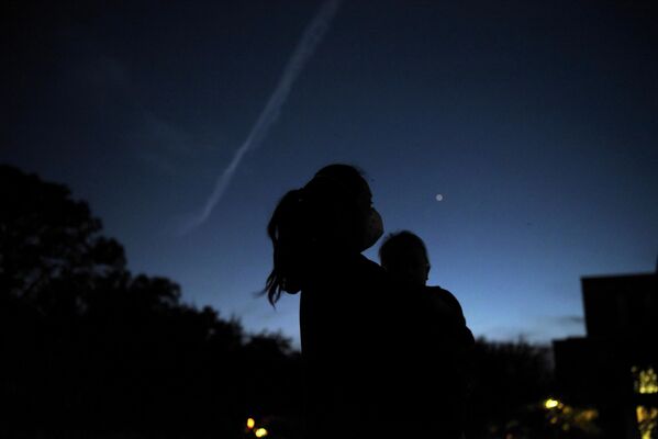 Женщина с ребенком наблюдают за встречей Юпитера и Сатурна  в Хьюстоне, штат Техас, США