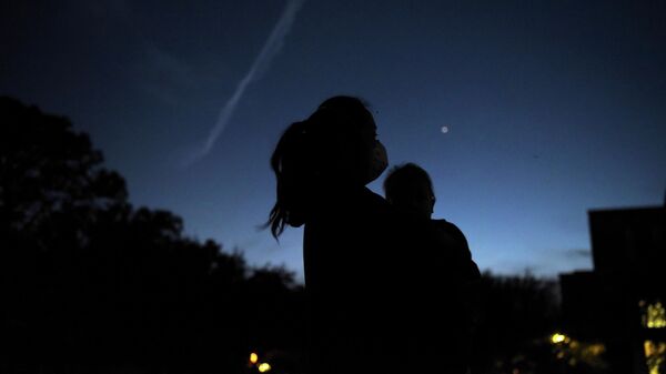 Женщина с ребенком наблюдают за встречей Юпитера и Сатурна  в Хьюстоне, штат Техас, США