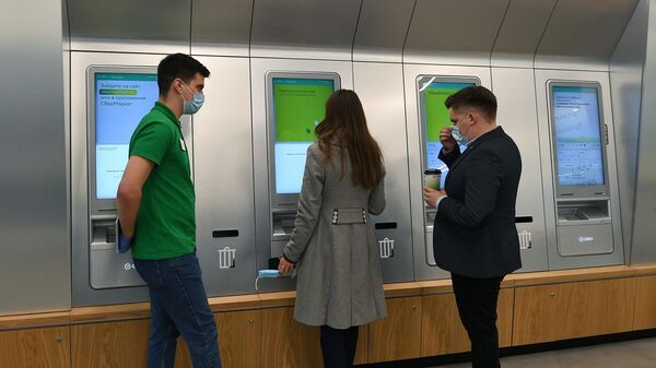 Посетители банка снимают деньги через банкоматы