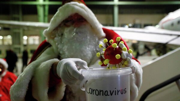 Санта-Клаус с игрушечной моделью коронавируса  в Берлине, Германия