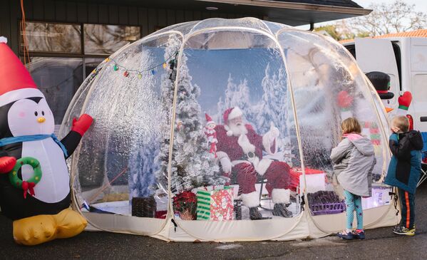 Мужчина в костюме Санта Клауса общается с детьми на украшенной к Рождеству улице в Сиэтле