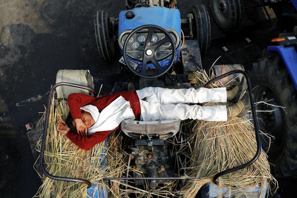 Сын фермера спит на тракторе во время акции протеста в Газиабаде, Индия