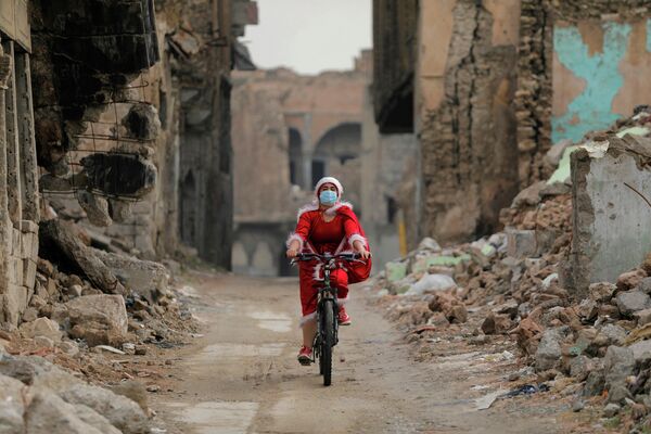 Иракская женщина в костюме Санта-Клауса, едет на велосипеде в Мосуле, Ирак