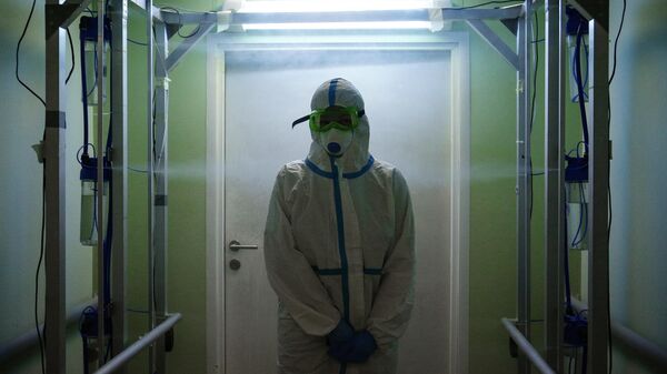 Медик в защитном противоэпидемическом костюме проходит санитарную обработку в красной зоне Новосибирской областной клинической больницы
