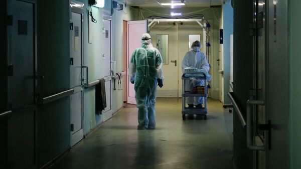 Медики в защитном противоэпидемическом костюме в коридоре Новосибирской областной клинической больницы