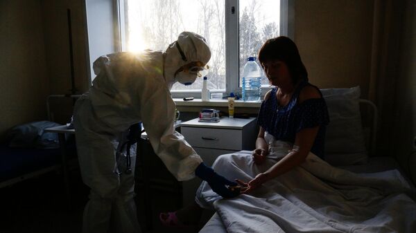 Врач замеряет пульсоксиметром сатурацию у пациентки в палате Новосибирской областной клинической больницы