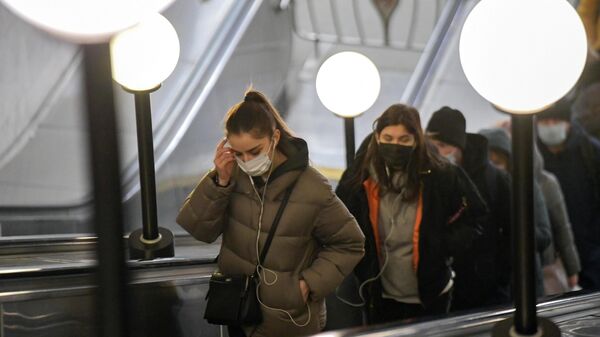 Пассажиры в защитных масках на эскалаторе в московском метрополитене