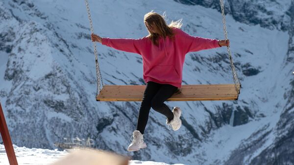 Девушка на качелях на горнолыжном курорте Домбай