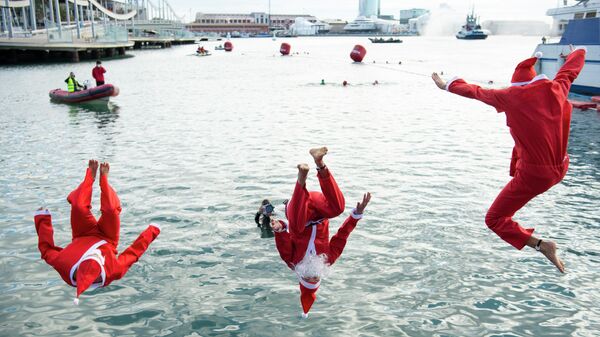 Мужчина в костюмах Санта-Клауса прыгают в воду во время 111-го соревнования по плаванию Copa Nadal в порту Велл в Барселоне. 25 декабря 2020