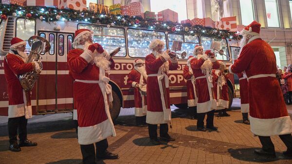 Музыканты в костюмах Дедов Морозов исполняют музыкальный номер у праздничного Дедморобуса, который ездит по улицам Санкт-Петербурга в преддверии нового года