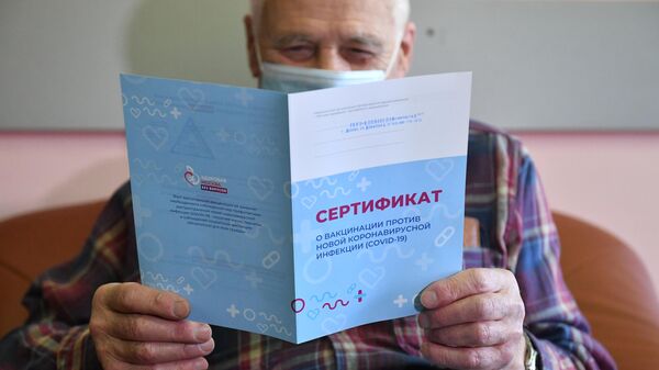 Мужчина держит в руках сертификат о вакцинации против коронавирусной инфекции (COVID-19)