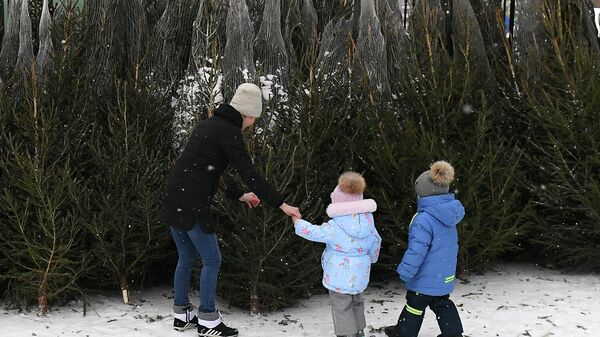 Женщина с детьми выбирают елку на елочном базаре