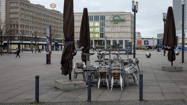 Столы и стулья возле закрытого кафе на площади Александерплац в Берлине
