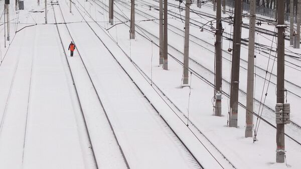Работник железной дороги обходит железнодорожные пути 