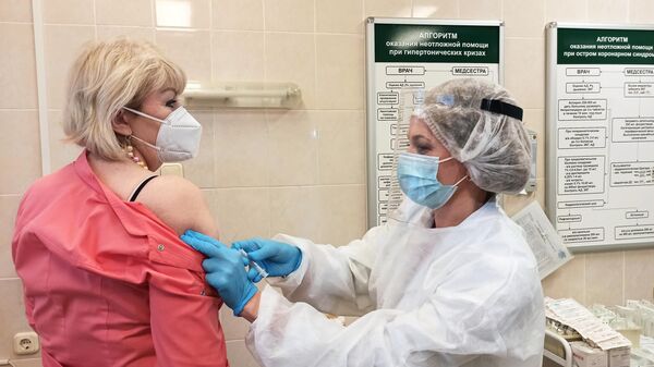 Медицинская сестра вводит женщине российскую вакцину от коронавируса Sputnik V (Гам-КОВИД-Вак) в процедурном кабинете в Минске