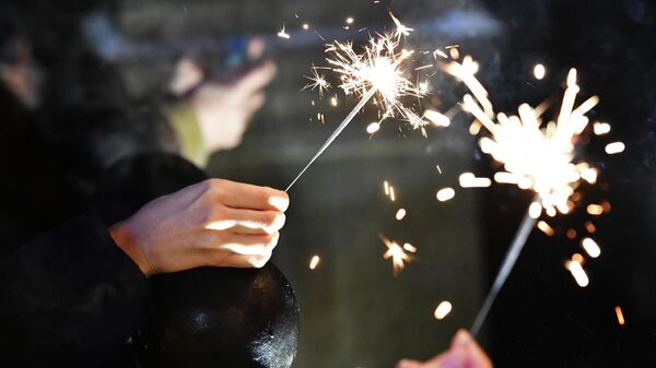 Бенгальские огни в руках людей, празднующих Новый год