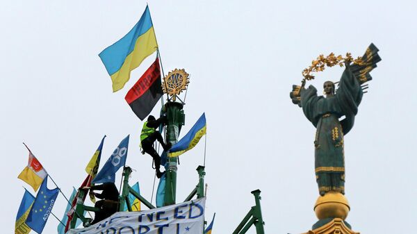 Активист проевропейского союза укрепляет украинский герб и флаг на металлической основе разрушенной елки во время митинга на площади Независимости в Киеве