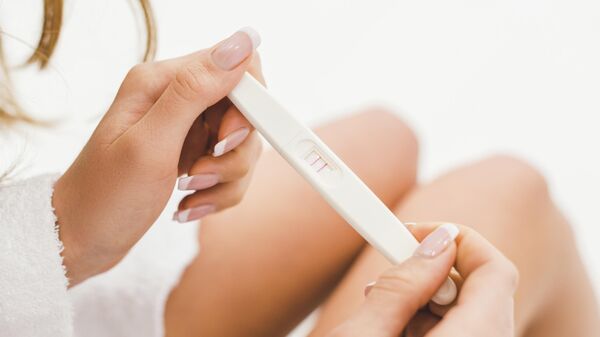 Женщина держит тест на беременность